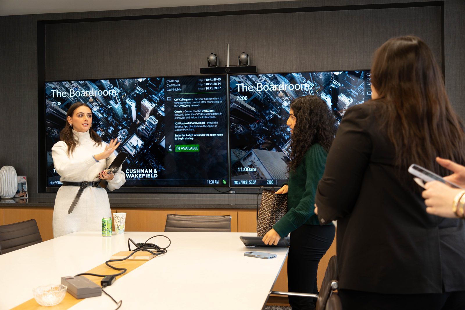 A presentation in front of two wall screens in a firm's boardroom.