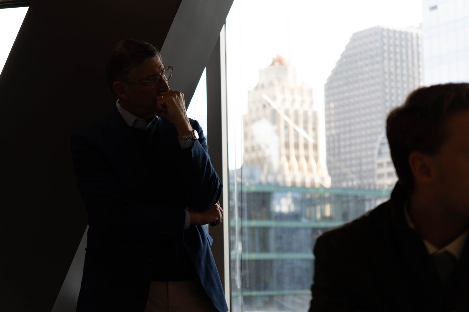 A guest speaker beside a window overlooking the city skyline.