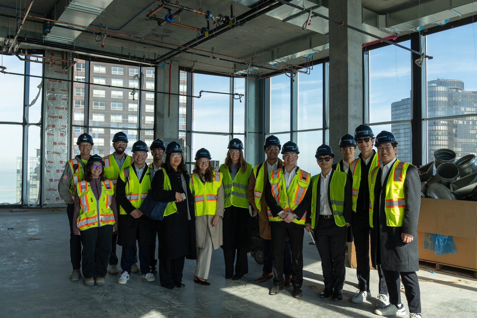 Members in hard hats and safety vests touring a construction site.