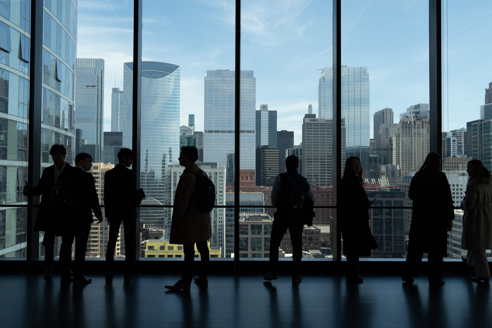 Members at floor-to-ceiling windows overlooking a downtown skyline.