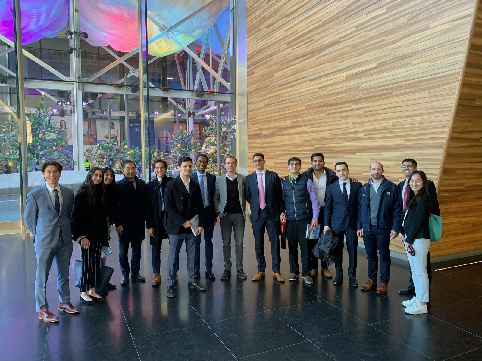 The group in a building lobby beside a wood-panelled wall.